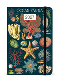 2027 Cavallini & Co. Ocean Fauna Weekly Planner has a dark teal cover decorated with vintage-style illustrations of sea stars, coral, shells, and marine life. A white label on the cover displays '2027'.