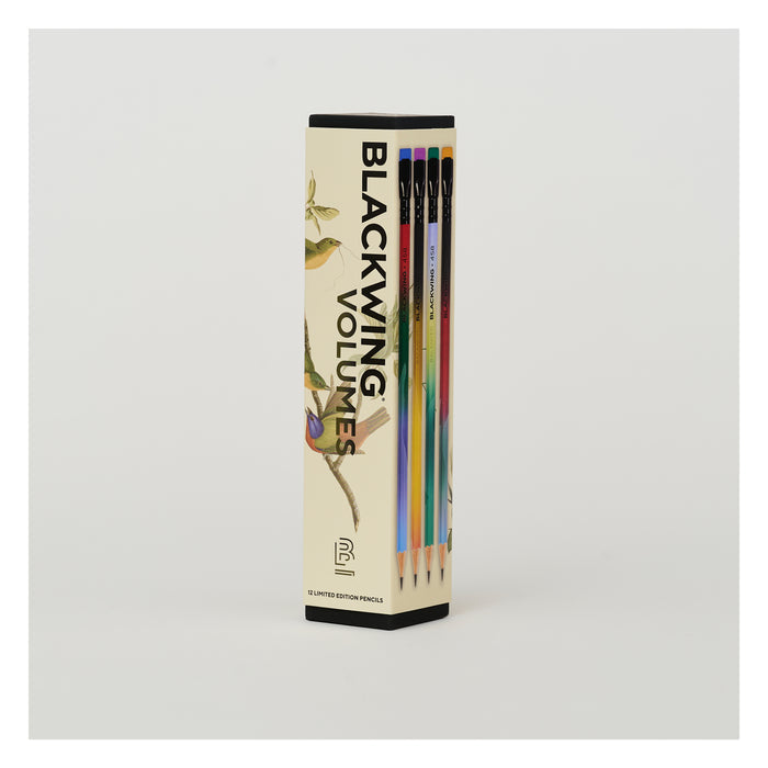 A boxed set of pencils standing upright in a tall rectangular package. The package is cream-colored with black text reading 'BLACKING VOLUMES' and illustrations of birds and branches.
