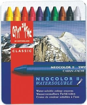 A set of Caran d'Ache Neocolor II water soluble pastels in a tin, with a mountainous landscape in the background.