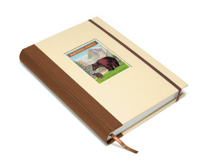 Notebook with a brown leather cover and a National Parks decorative label in the window on a white background