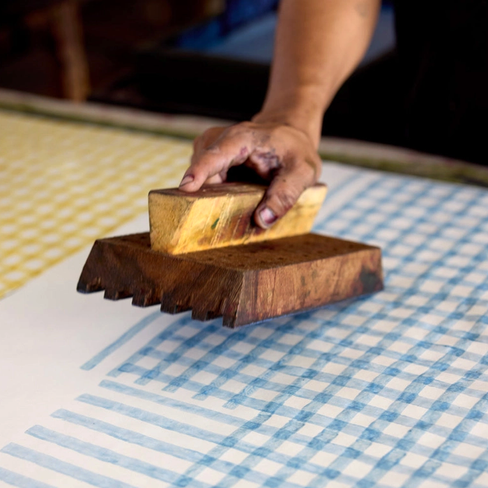 Hand using a wooden block creating checker board pattern in blue