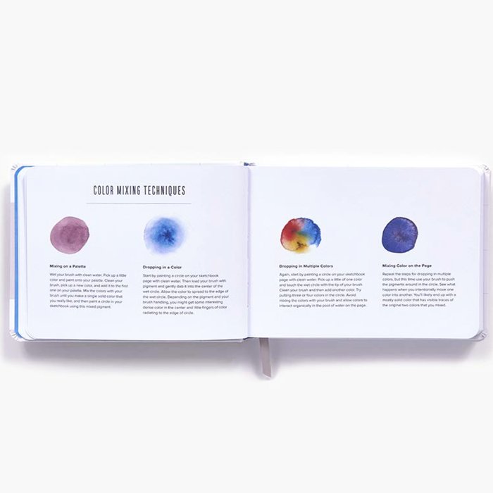 An open art instruction book showing pages titled 'Color Mixing Techniques' with watercolor swatches and explanatory text, photographed on a clean white background.