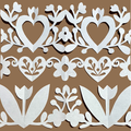 White paper cutout decorative border with hearts, flowers, leaves, and tulips arranged in horizontal rows on a solid brown background.