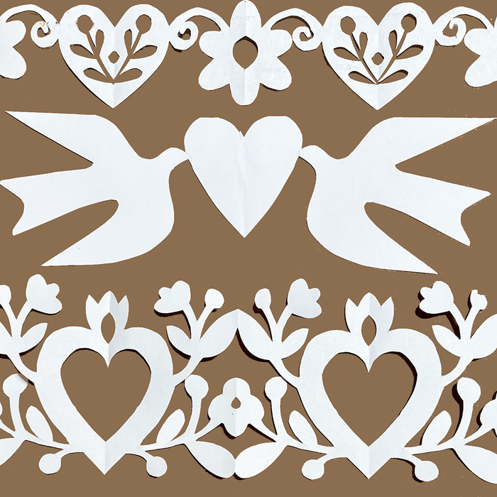White paper cutout designs featuring two doves with a heart between them, surrounded by ornate heart and floral patterns, displayed on a solid brown background.