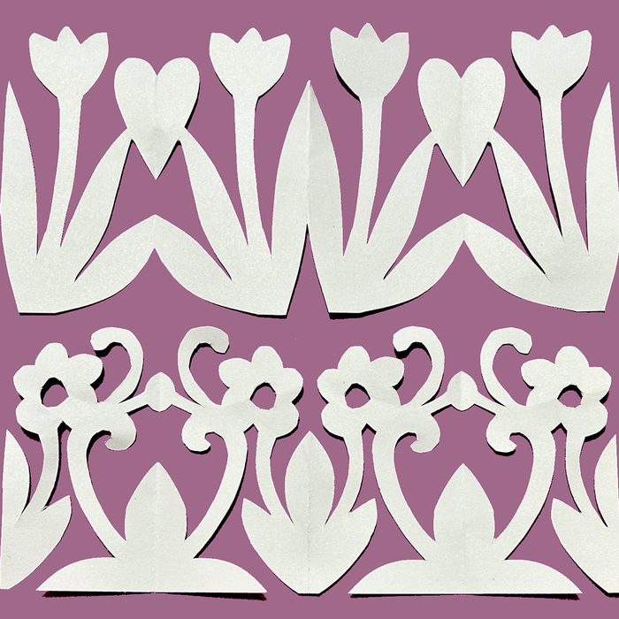 White paper cutout floral and scroll border designs arranged in two rows on a solid mauve-purple background.