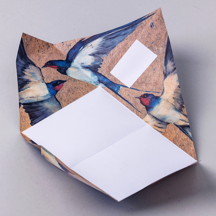 Colorful origami folded letter shown open with swallow themed design on a light gray background