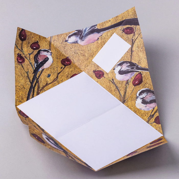Colorful origami folded letter shown open with long-tailed tit themed design on a light gray background