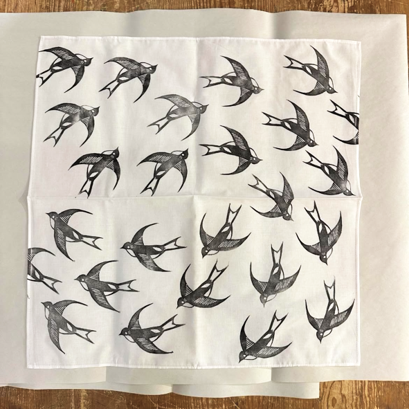 White fabric with black bird pattern on a wooden surface