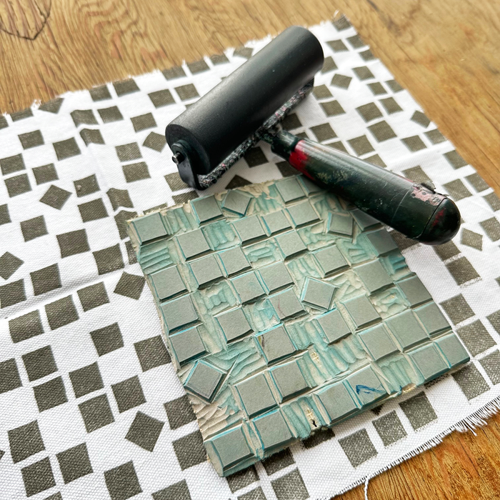 Printing on Fabric class sample of block printed checkerboard  with printing block on top of fabric with ink brayer.
