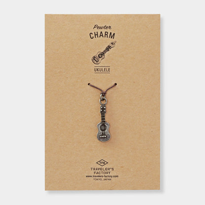 Ukulele-shaped charm on a brown card with 'Traveler's Factory' branding.